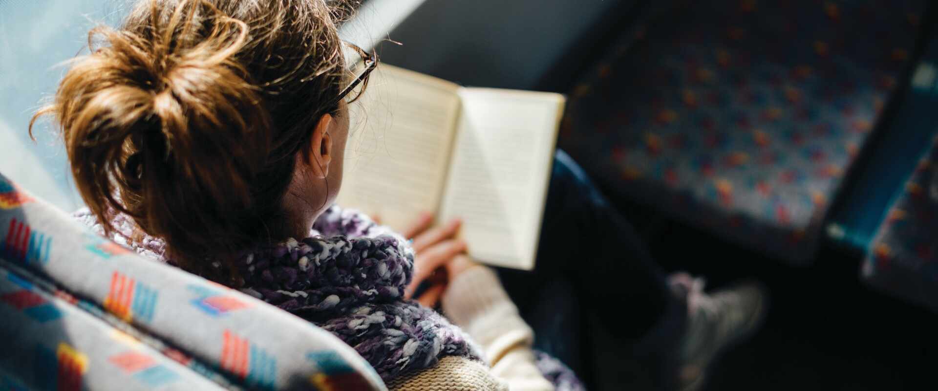 Person reading book on train